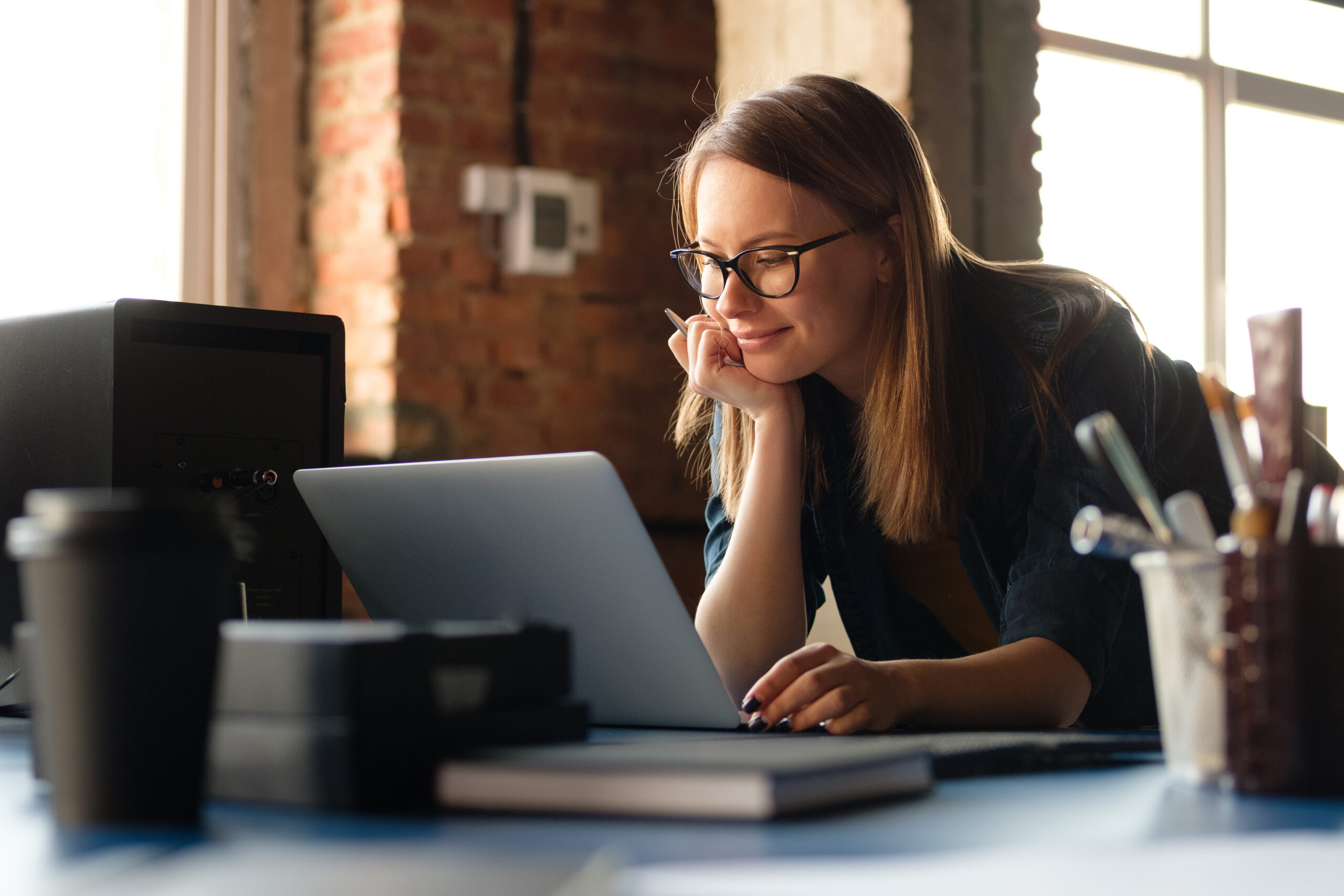 A woman is checking journal entries at a computer in a modern office