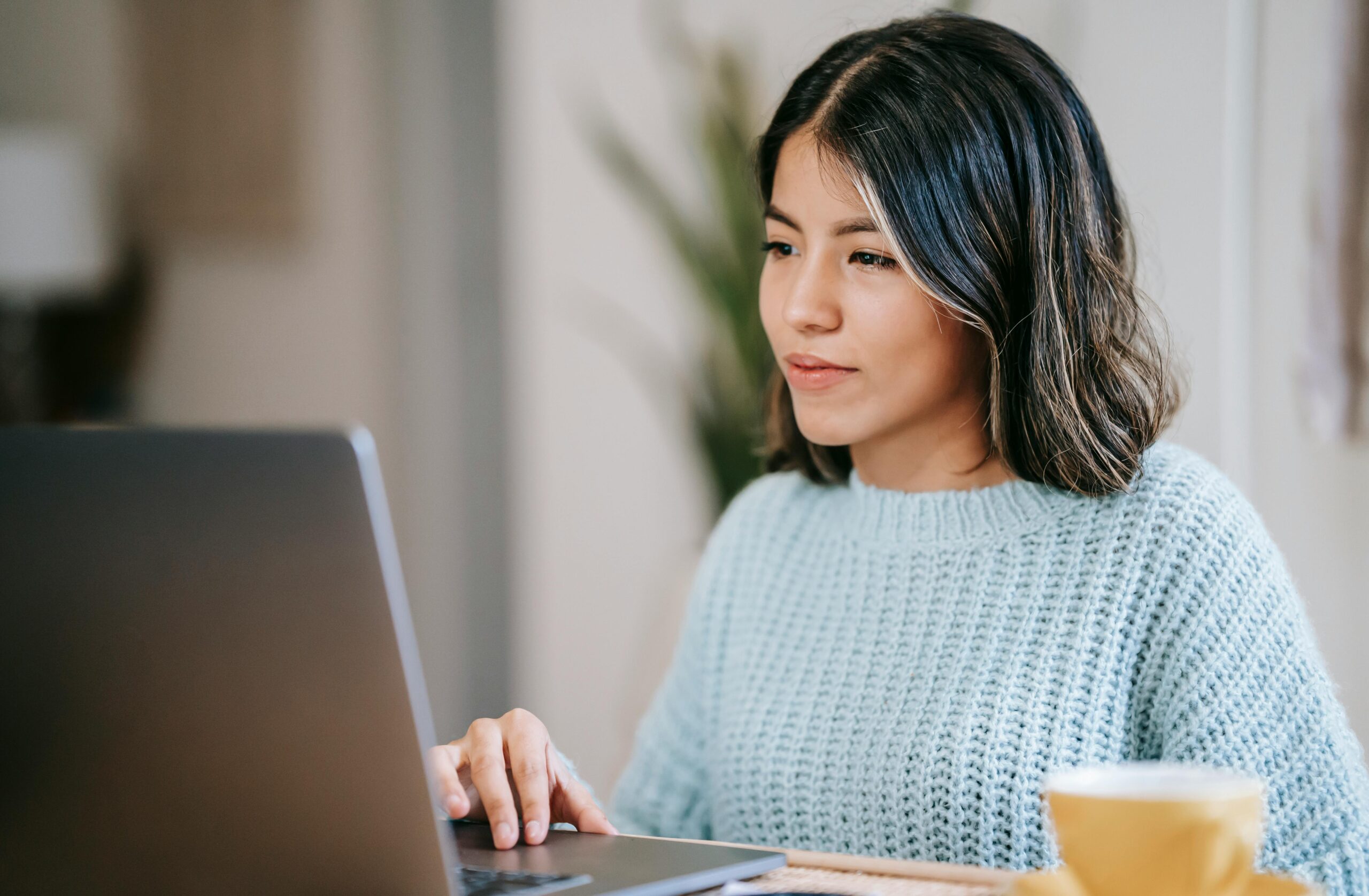 Young woman smiling at her laptop while performing payroll reconciliation