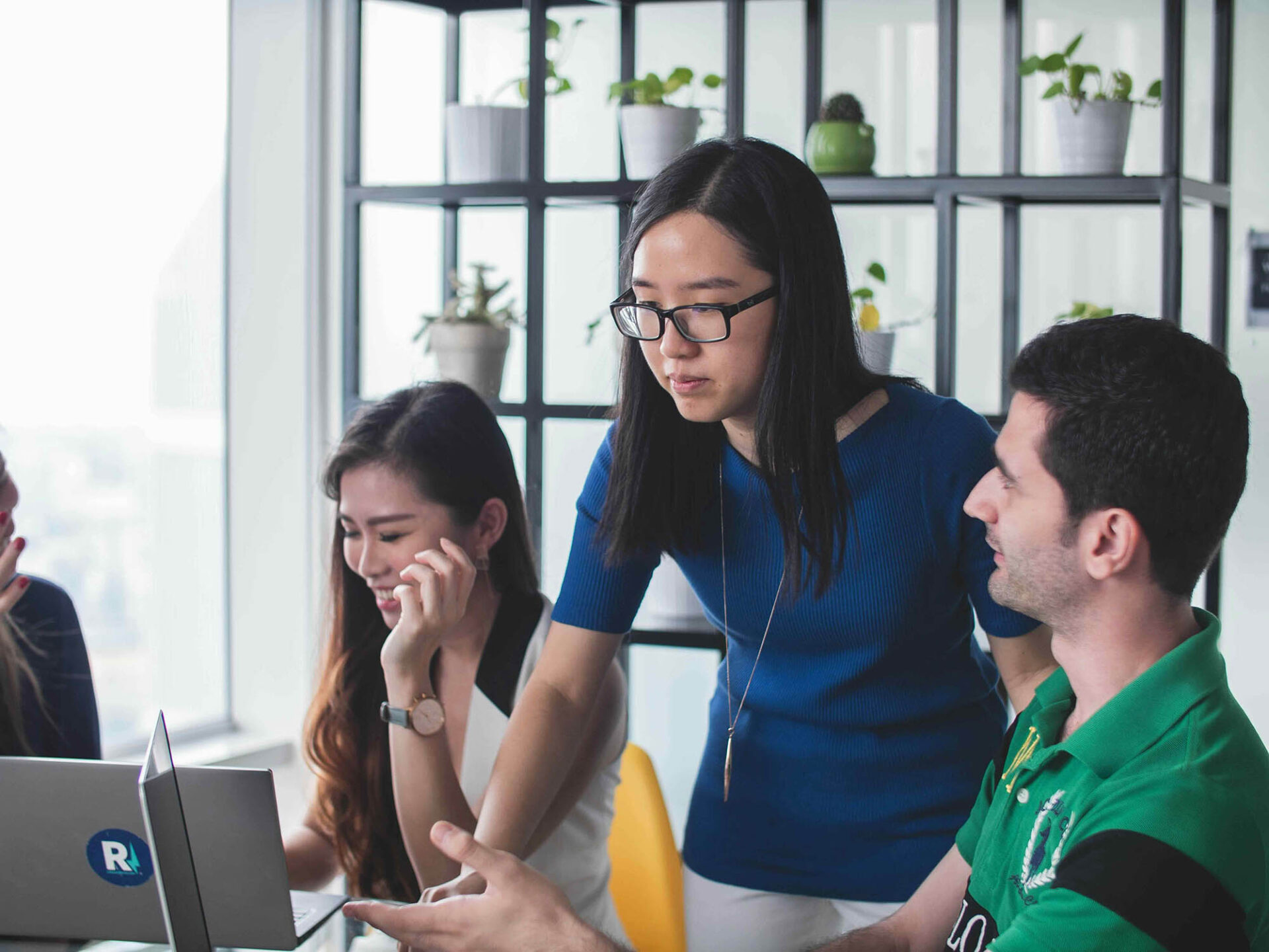 Coworkers collaborating on laptops in office to manage transaction reconciliation tasks